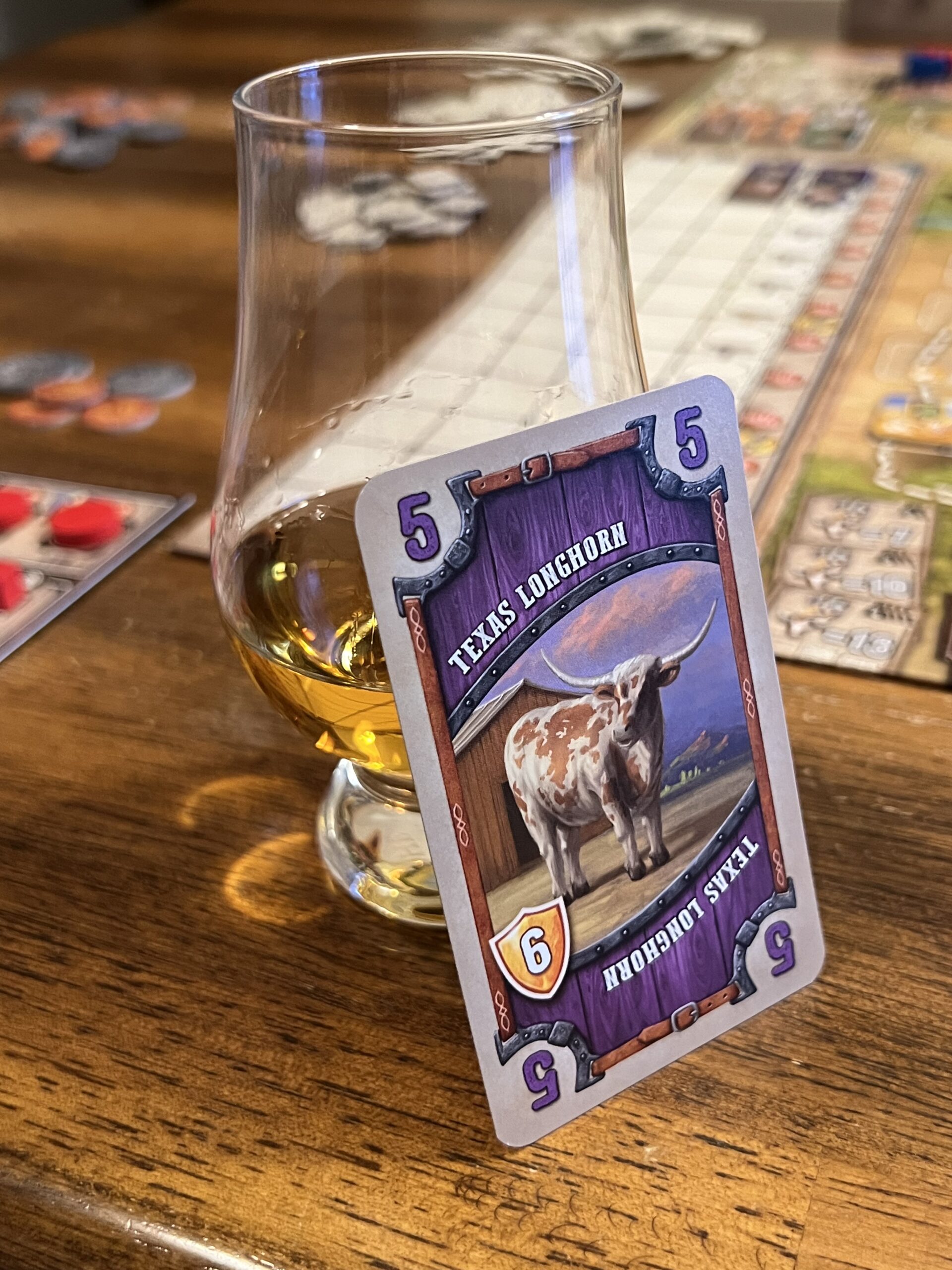 A card with a picture of a Texas Longhorn leaning against a glass of whiskey.