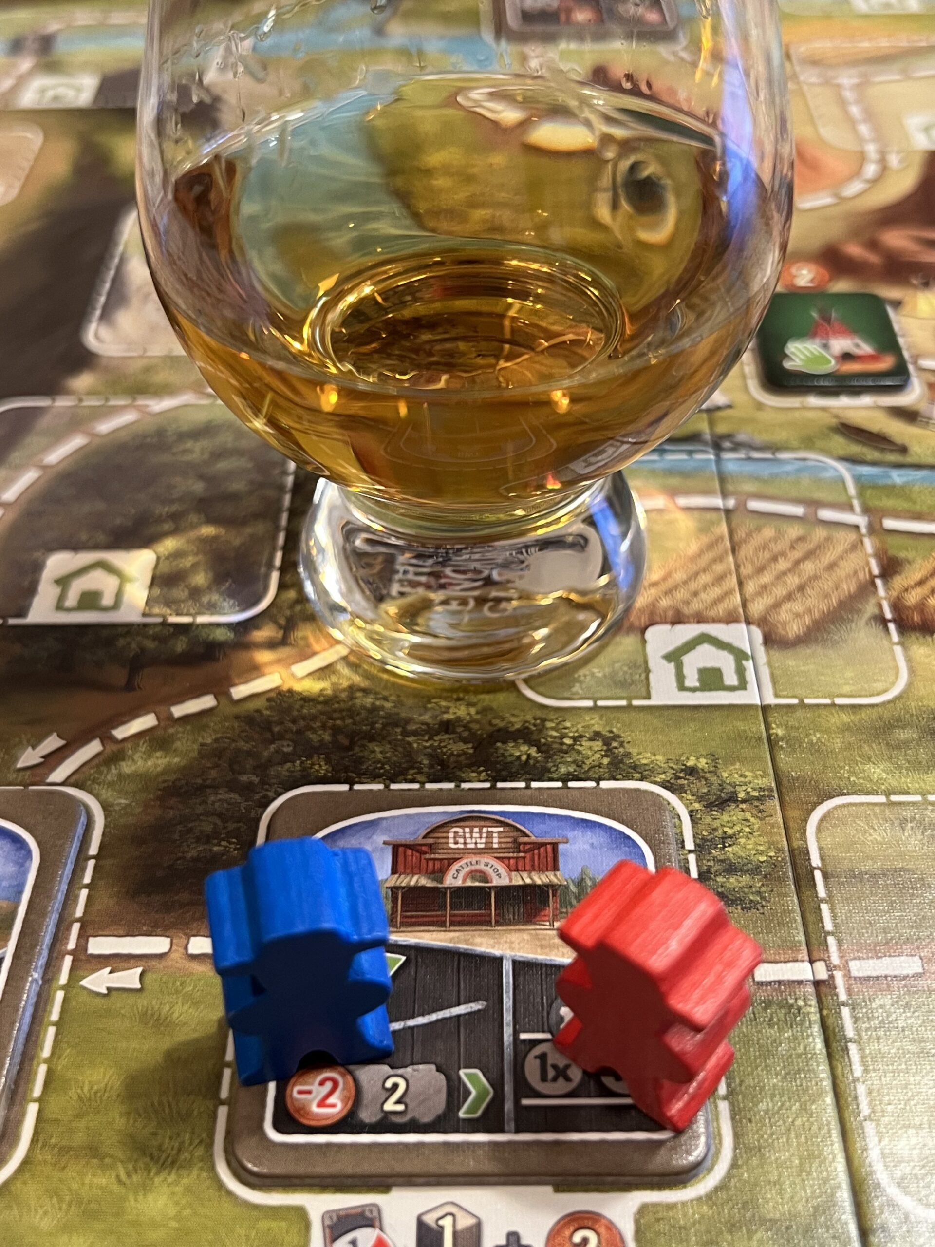 Board game pieces on a board and a glass of whiskey.