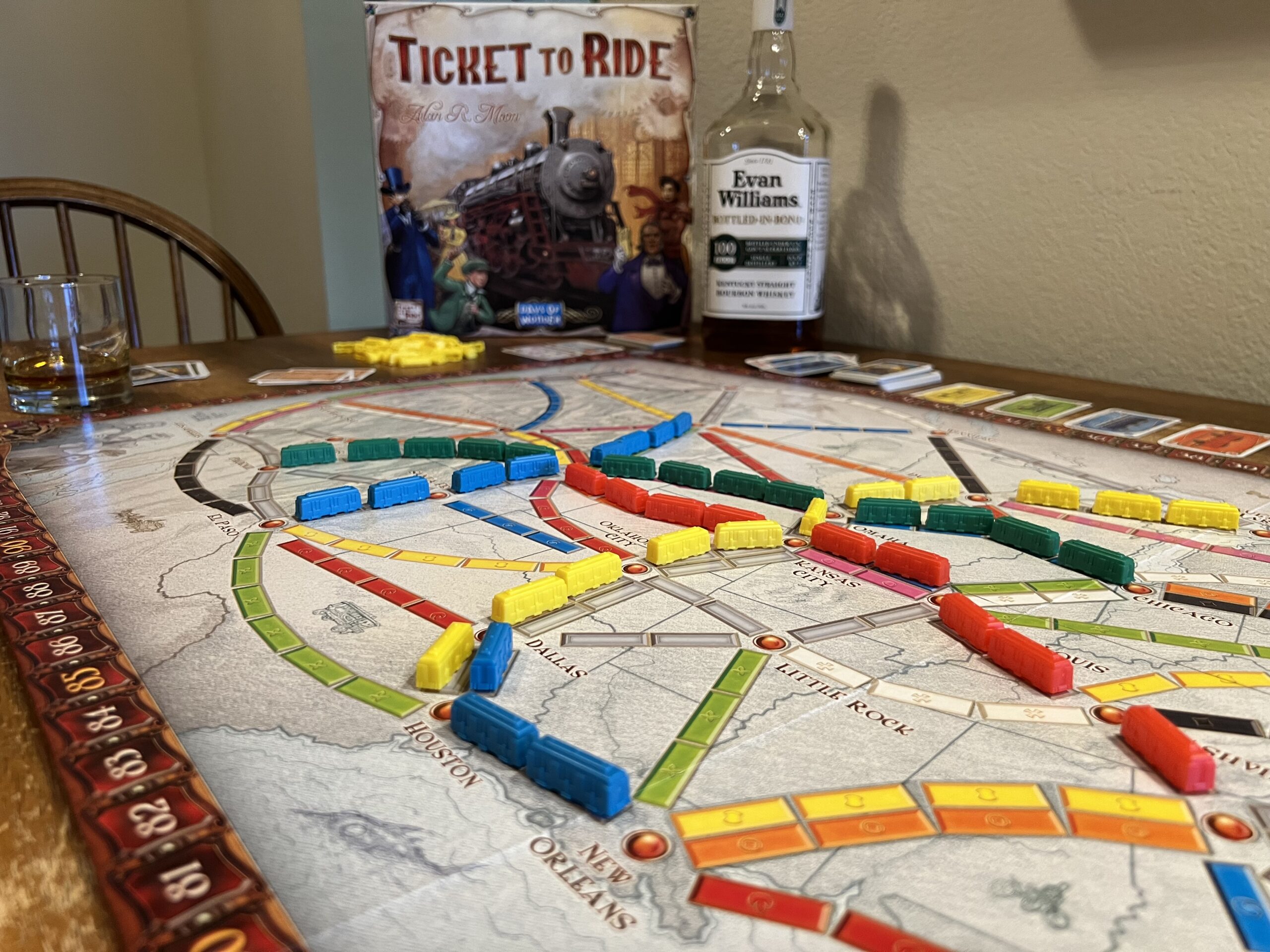 A game of Ticket to Ride in the foreground with a bottle of Evan Williams in the background.